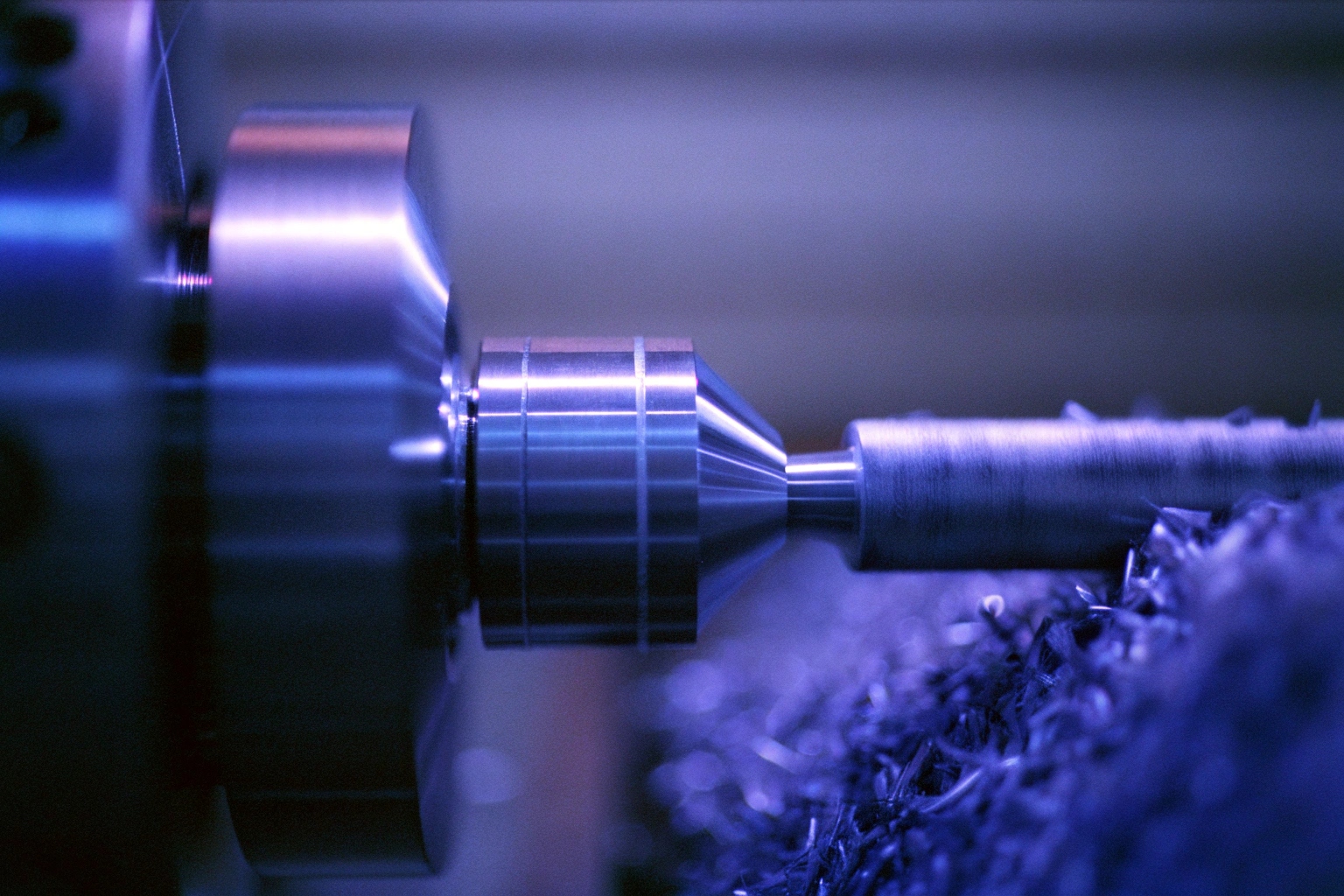 Close-up of precision lathe machining metal piece in industrial setting.