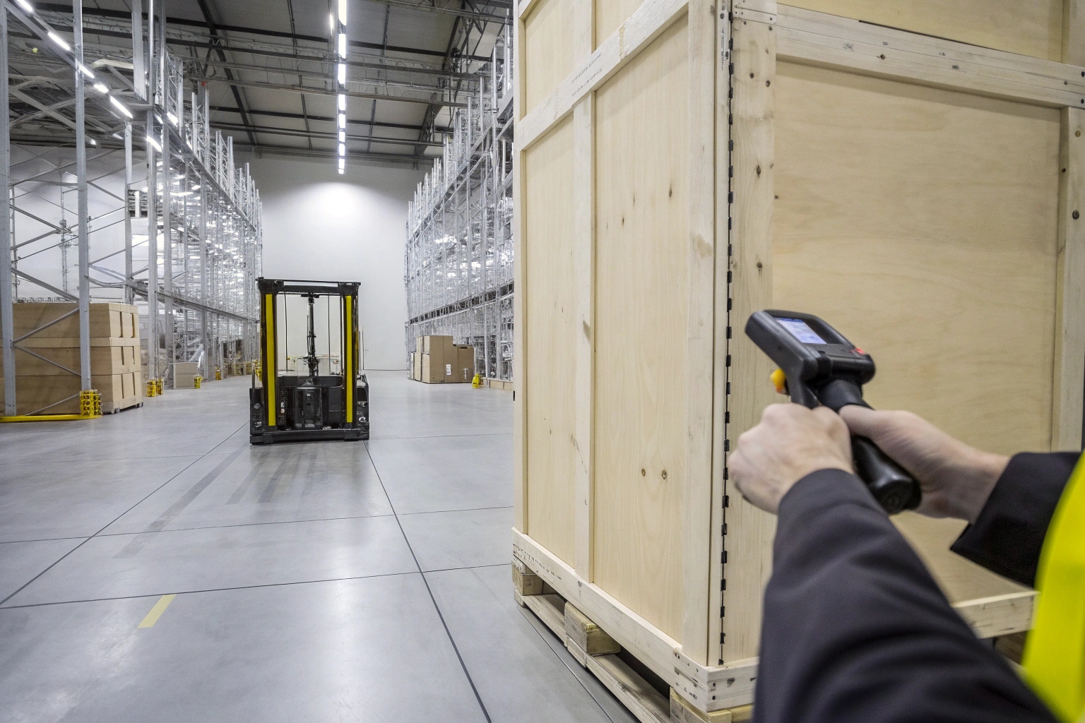 Warehouse worker scanning a large wooden shipping crate with a handheld barcode reader.