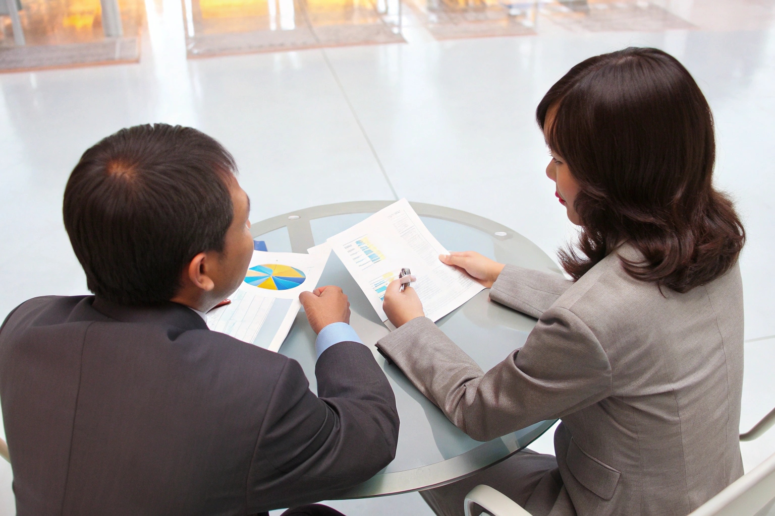 Two business colleagues analyzing financial charts and reports at a meeting.