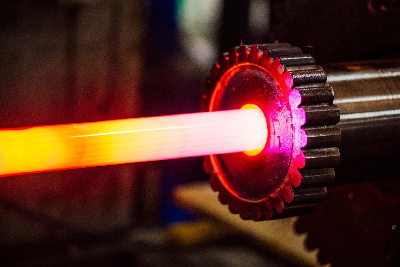 Metal sprocket undergoing induction hardening heat treatment for increased durability.