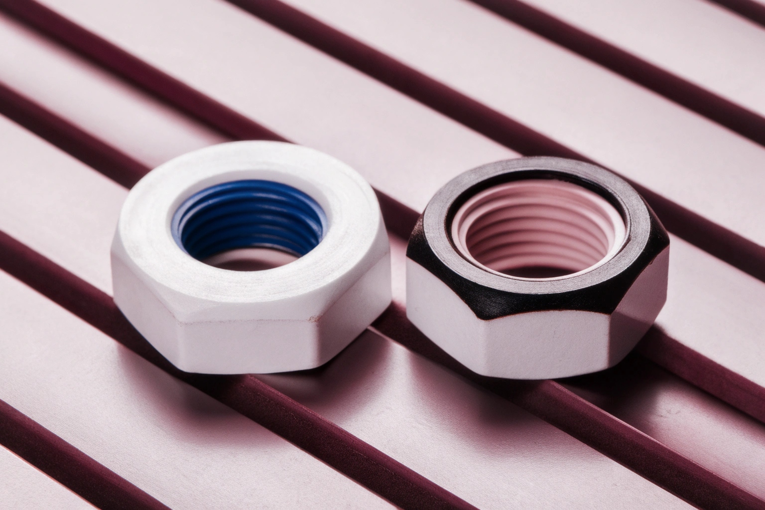 Macro photo of two different colored nylon insert hex lock nuts on a metal surface.