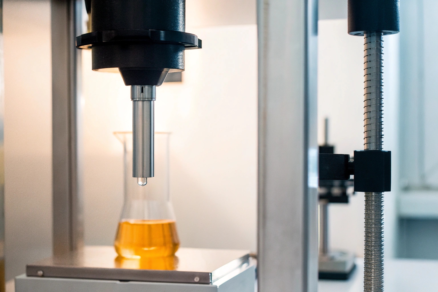 Laboratory equipment testing the viscosity or chemical properties of an industrial oil in a beaker.