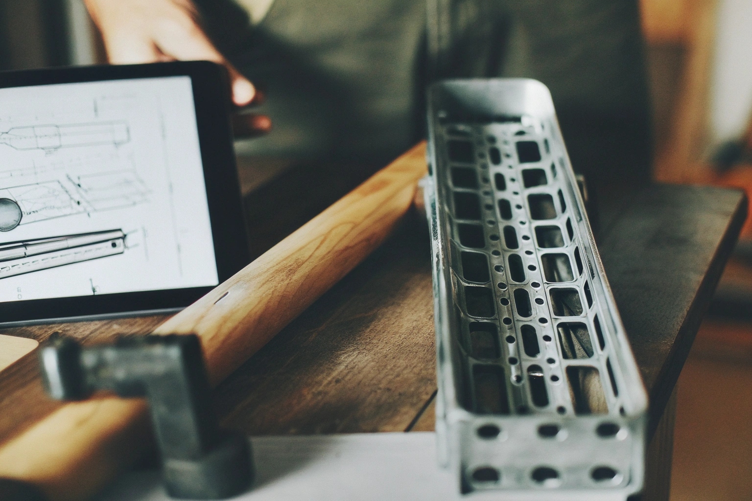 Engineer designing a customized, reinforced track shoe part using a technical drawing on a tablet.