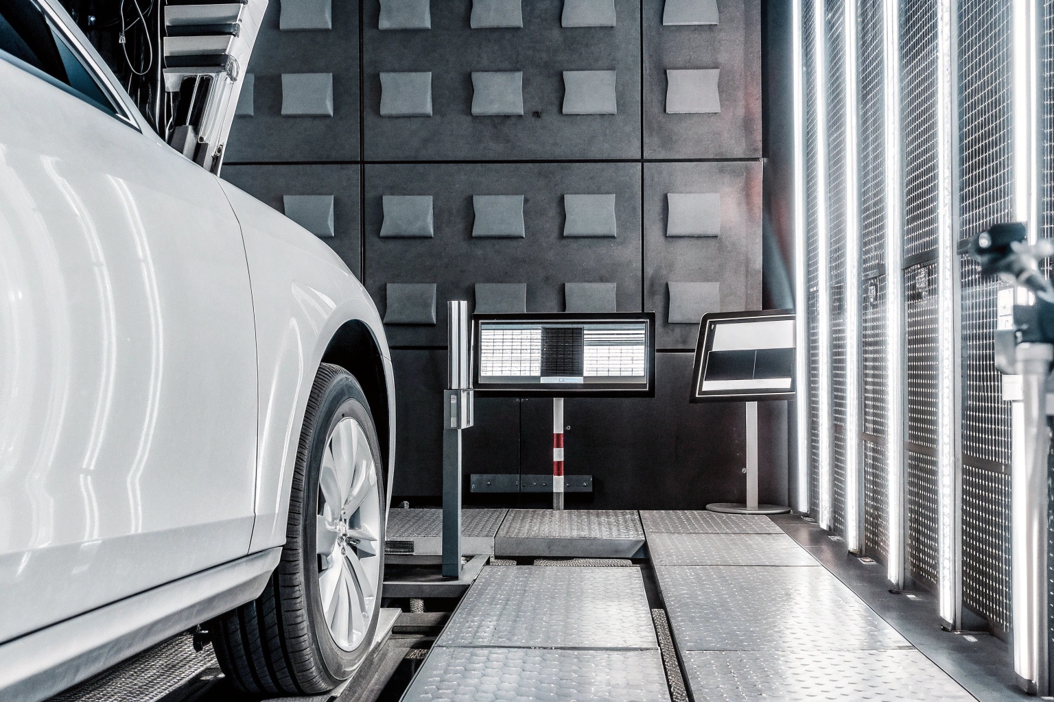 White car on a chassis dynamometer in a vehicle testing laboratory for quality control.