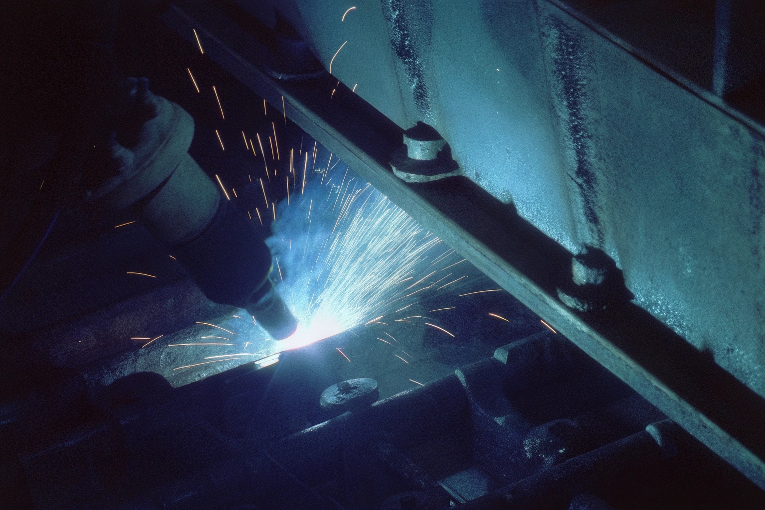 Close-up of automated welding process on heavy steel components creating bright sparks.